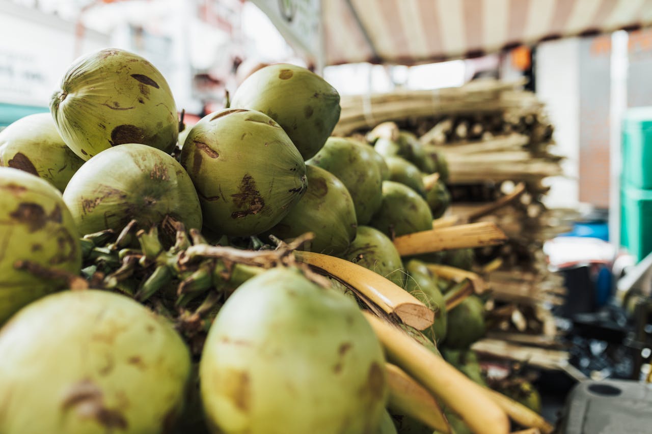 Close-up of fresh green coconuts stacked at an outdoor market stall, exuding a tropical vibe.